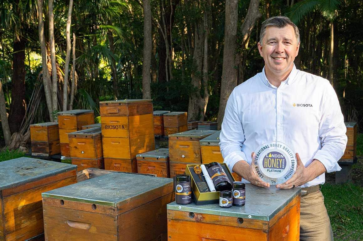 A member of the Biosota family at the hives with the 2026 London Honey Awards Platinum trophy