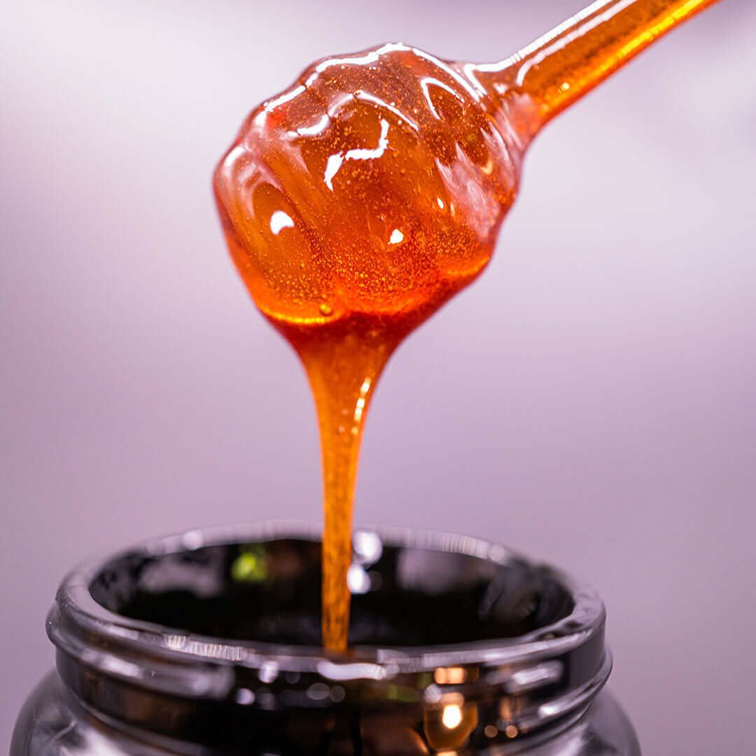 Manuka honey dripping from a dipper into a jar